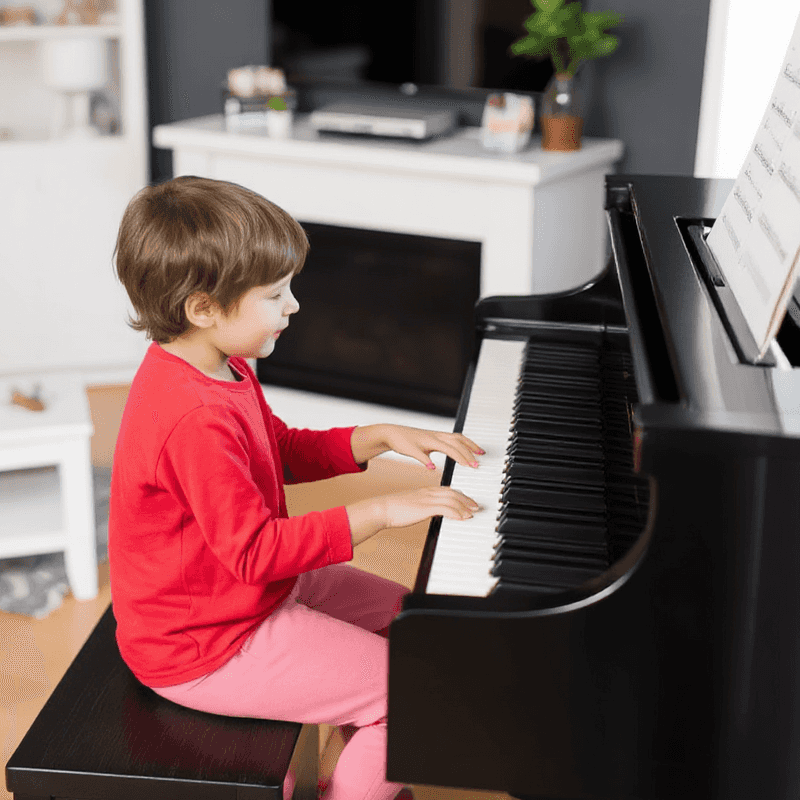 little boy wearing a red shirt playing an upright piano.png